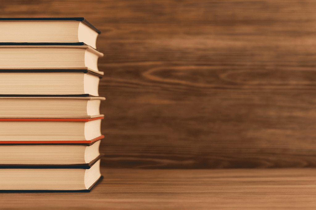 A stack of hardcover books on a wooden surface with a warm wooden background, representing a curated collection of biohacking books for health and longevity.